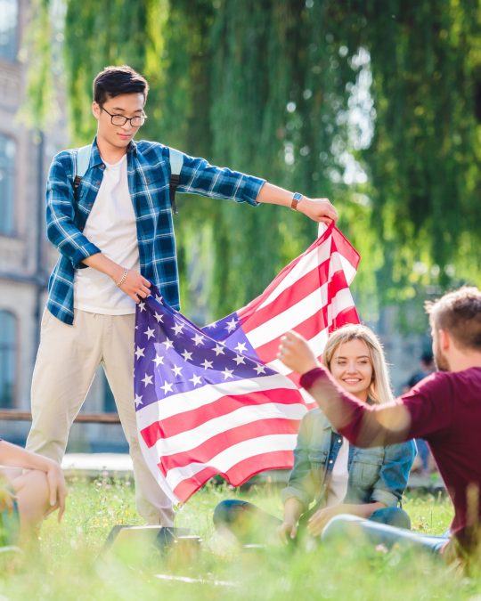 multicultural-students-with-american-flag-in-summer-park.jpg